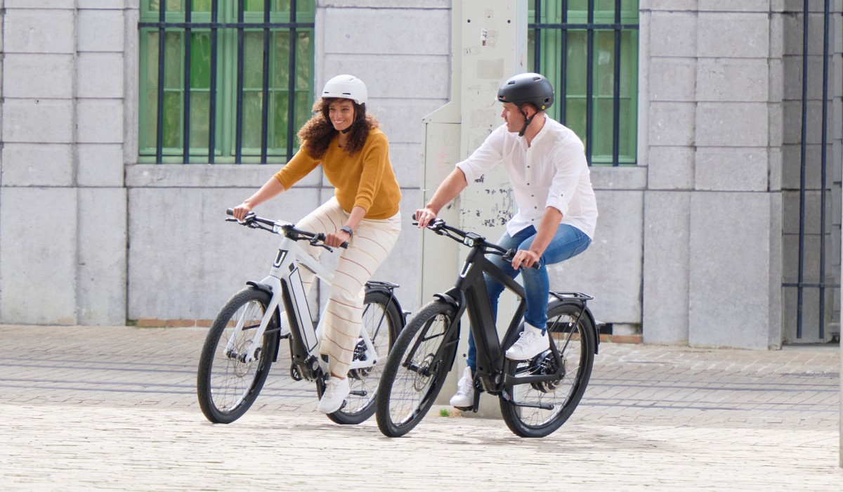 Une femme et un homme roulent en ville avec leur vélo électrique rapide Stromer ST3, atteignant 45 km/h.