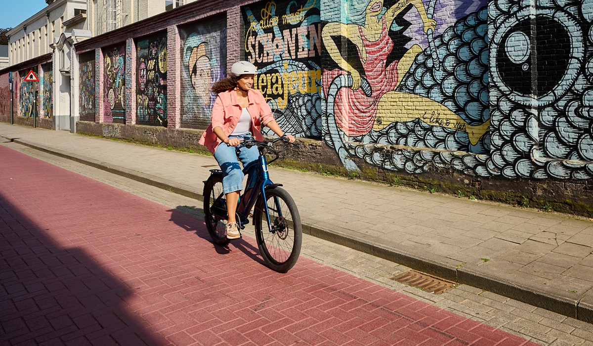 Une femme roule sur un vélo électrique Stromer ST1 à grande vitesse, avec une autonomie de 90 km.