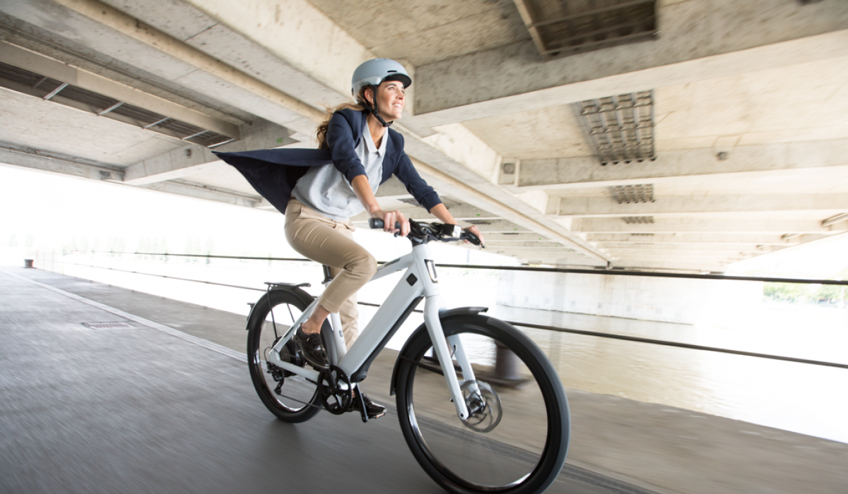 Woman on a white ST3 riding under a bridge