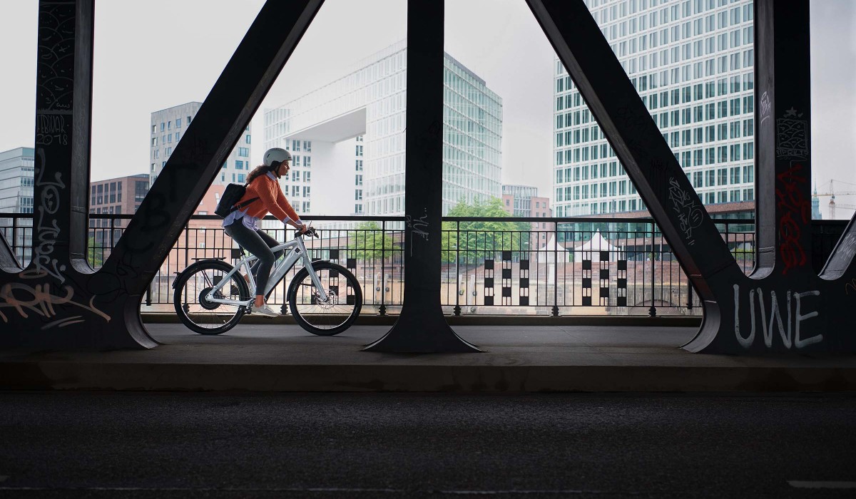 Une femme parcourt la ville avec son Stromer ST3 Pinion – avec une autonomie jusqu'à 150 km, optionnellement extensible jusqu'à 180 km.