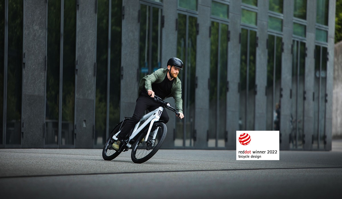 Un homme roule devant un bâtiment avec un Stromer ST3 dans la couleur Cool White.